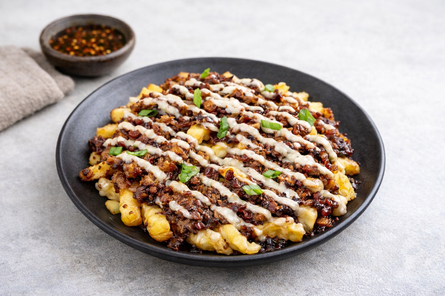 Loaded fries topped with tender pork adobo, candied bacon, scrambled eggs, green onions, and a creamy sauce drizzle in a takeout box.